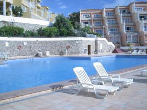 a swimming pool with two chairs and a building at Vaso Rojo vista mar in Adeje