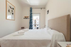 - une chambre blanche avec un grand lit et des serviettes dans l'établissement Trindade Sun Guesthouse, à Lagos