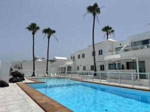 a swimming pool in front of a building with palm trees at Barraquito - Pool - 100M to Playa de Las Cucharas By Lanzarote Vacation Homes in Costa Teguise
