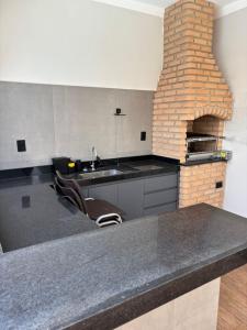 a kitchen with a sink and a brick fireplace at Ótima casa Termas Olímpia in Olímpia