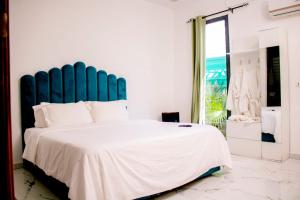 a bedroom with a large bed with a blue headboard at Résidences Millenium Suites Yakro in Yamussukro