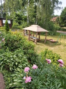 a picnic shelter in a garden with pink flowers at Leśne Zacisze in Kretowiny +15 photos