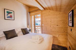 Schlafzimmer mit einem weißen Bett und Holzwänden in der Unterkunft Simply Morzine - Chalet Petit Central in Morzine
