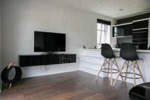 a kitchen with two bar stools and a flat screen tv at Pärnu Lubja Apartments in Pärnu