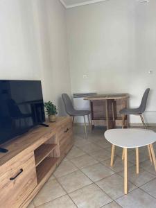 Una sala de estar con televisión, mesa y sillas. en The Cozy Central Home, en Xanthi