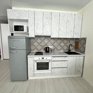 a kitchen with a refrigerator and a microwave at A cozy and bright studio apartment in Chornomorsk