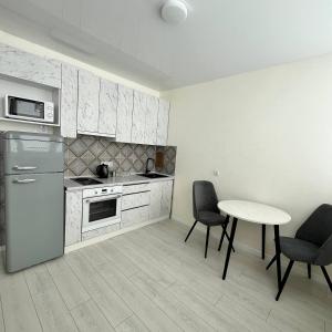 a kitchen with a table and two chairs and a refrigerator at A cozy and bright studio apartment in Chornomorsk