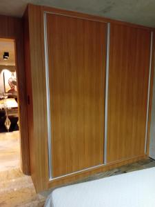 un armadio in legno con porte in vetro accanto a un letto di Flatpremium1501 a Fortaleza