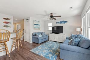 a living room with a blue couch and a tv at Aqua Adventure in Kill Devil Hills