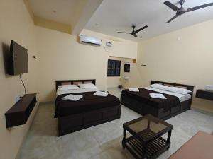 a room with two beds and a flat screen tv at Malathi Residency in Arumuganeri
