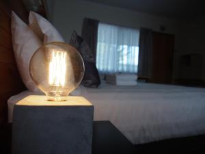 a lamp on a table in a bedroom with a bed at Majestic Motel in Horsham