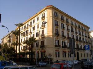 a large yellow building with cars parked in front of it at Caracciolo 10 in Naples