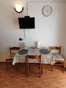 a dining room table with two chairs and a clock on the wall at Apartman Dide in Igrane
