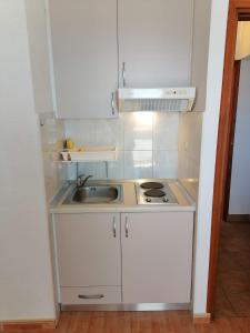 a small kitchen with white cabinets and a sink at Apartman Dide in Igrane