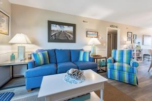 Una sala de estar con un sofá azul y una mesa. en Aquaholic, en Kill Devil Hills