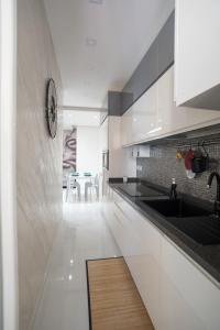 una cucina con mobili bianchi e un lavandino di Dimora Santi e Marinai a Bari