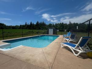 a swimming pool with two lounge chairs next to it at Silverwood Motel in Cavendish