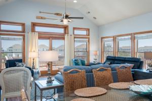 ein Wohnzimmer mit Sofa, Stühlen und Fenstern in der Unterkunft Blue Moon in Nags Head