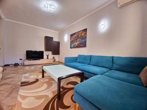 a living room with a blue couch and a table at Elly Apartment in Durrës