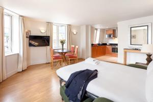 a bedroom with a bed and a table and a kitchen at Marlin Apartments London City - Queen Street in London +6 photos
