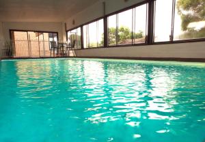 a swimming pool with blue water in a building at Majestic Motel in Horsham