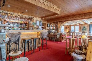 Un bar con taburetes en una habitación con techos de madera. en Hôtel Ecureuil, en Vars 82 fotos más