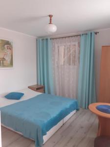 a bedroom with a bed and a window with blue curtains at Przystanek Dąbki in Dąbki