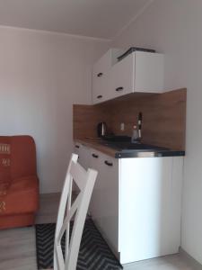 a small kitchen with a sink and a chair at Przystanek Dąbki in Dąbki