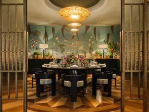 a dining room with a table and chairs and a chandelier at Rocco Forte The Charles Hotel in Munich