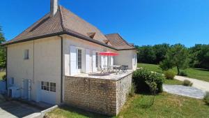 een wit huis met een tafel en een rode paraplu bij Grande Périgourdine, très grand jardin au calme in Bergerac
