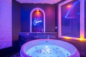 a bathroom with a large tub with a neon sign at Suite jungle amour détente in La Flèche