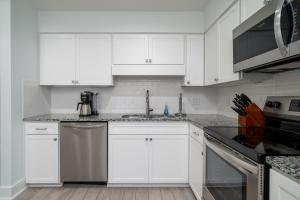 a white kitchen with white cabinets and a sink at 1147 Summerwind Cottage in Seabrook Island +27 photos