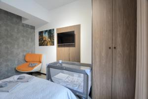 a bedroom with a bed and a chair and a tv at Premium Apartment Eleven in Zator