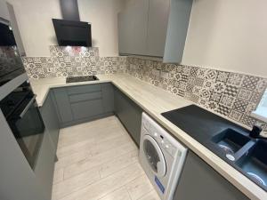a kitchen with a sink and a washing machine at Elegant 4-Bedroom Apartment at Kexgill in Preston