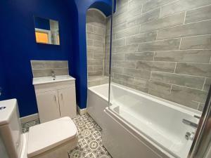 a bathroom with a tub and a toilet and a sink at Elegant 4-Bedroom Apartment at Kexgill in Preston
