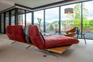 sala de estar con sofá rojo frente a las ventanas en La Plâtrière, appartement classé 5 étoiles, avec garage en ville haute du Puy, en Le Puy en Velay