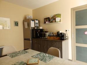 a kitchen with a table and a refrigerator at Étape premium confort avec parking et entrée privative in Sassenay