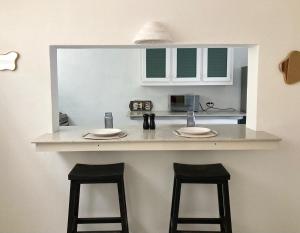 a kitchen counter with two stools and a sink at Maple cottage in Bridgetown +19 photos
