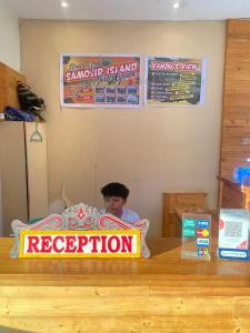 图克图克Vandu's View Guest house & Restaurant的坐在桌子上,带有标志的人