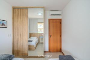 a mirror in a room with a bed and a bedroom at Apto em condomínio beira-mar Itacimirim-BA IAB109 in Camacari