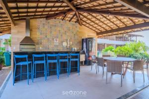 a patio with a bar with blue stools at Apto em condomínio beira-mar Itacimirim-BA IAB109 in Camacari
