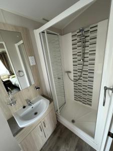 a white bathroom with a sink and a shower at Poplars 33, 3 Bedroom Luxury Caravan Trecco Bay Porthcawl in Porthcawl +25 photos