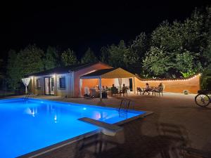 a swimming pool at night with people sitting around a table at Αρετή in Amaliás