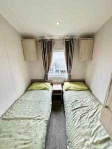two beds in a small room with a window at Poplars 33, 3 Bedroom Luxury Caravan Trecco Bay Porthcawl in Porthcawl