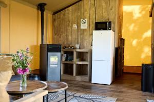 a living room with a refrigerator and two tables at Glamping Franse Peer in Hasselt