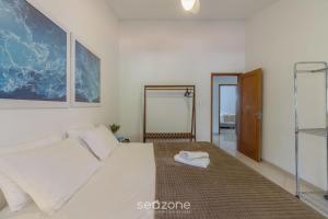 a bedroom with a white bed and a mirror at Casa 6Q pé na areia em Bombinhas ABM0101 in Zimbros