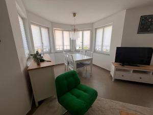 a living room with a green chair and a table at Großes Apartment 74m2 mit Balkon & Parkplatz - Steakhouse Esmeralda in Ebersbach-Musbach