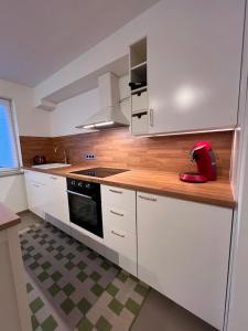a kitchen with white cabinets and a red appliance at Großes Apartment 74m2 mit Balkon & Parkplatz - Steakhouse Esmeralda in Ebersbach-Musbach