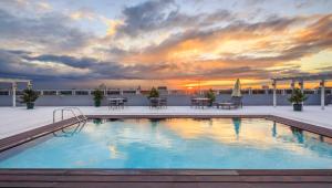 a pool on the roof of a building with a sunset at Microtel by Wyndham UP Technohub in Manila