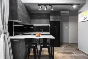 a kitchen with black cabinets and a table with chairs at "HoMes" II, The aRt BoutiQue experience by Lou Lenny in Kallithea Halkidikis